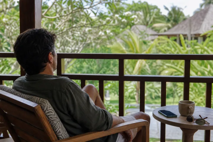 Persona in vacanza su un balcone con smartphone appoggiato lontano su un tavolino.