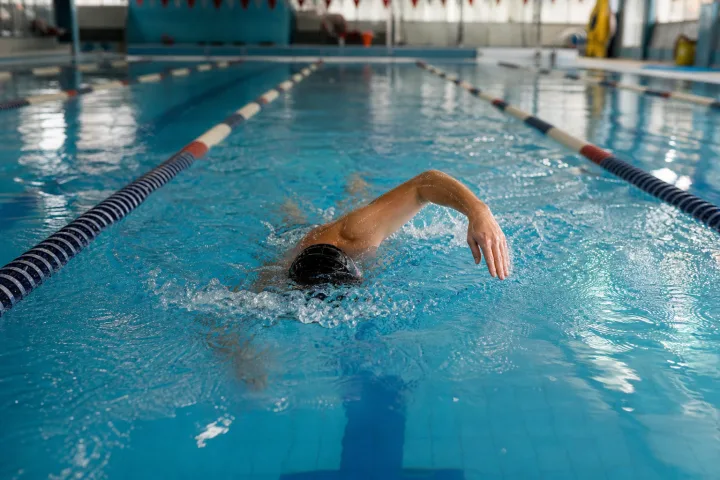 Nuotatore adulto in corsia durante una vasca facile in piscina coperta.