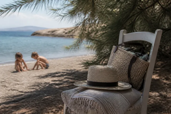 Sedia leggera con cappello e telo in una zona d'ombra naturale vicino alla spiaggia